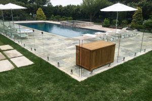 Earthscapes outdoor living services of a pool, glass fence, hot tub, and masonry tanning deck in Westport, CT